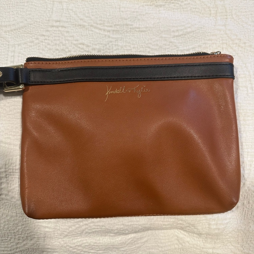 Kendall & Kylie Brown wristlet with black detail, adjustable strap.